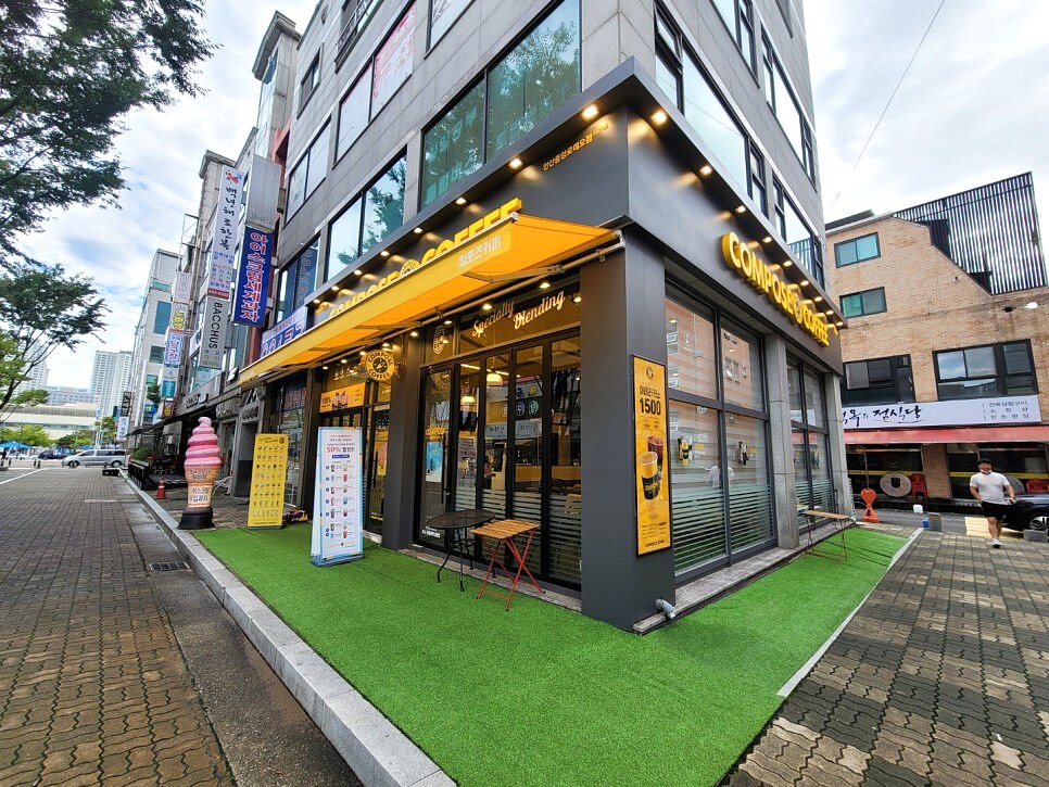 안산 컴포즈커피 매장 측면 전경과 트인 개방감, 야외 잔디