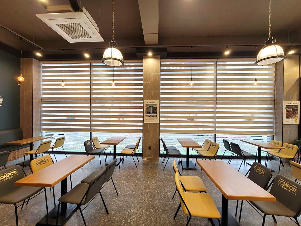 층고 높은 카페 통창 전면에 정렬된 우드룩 콤비블라인드