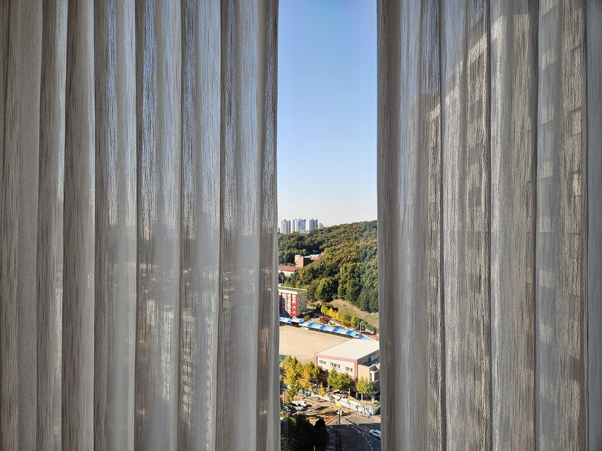 안산 한화포레나 거실 속커튼 사이로 보이는 안산 시내 풍경, 양옆으로 속커튼의 세로 결