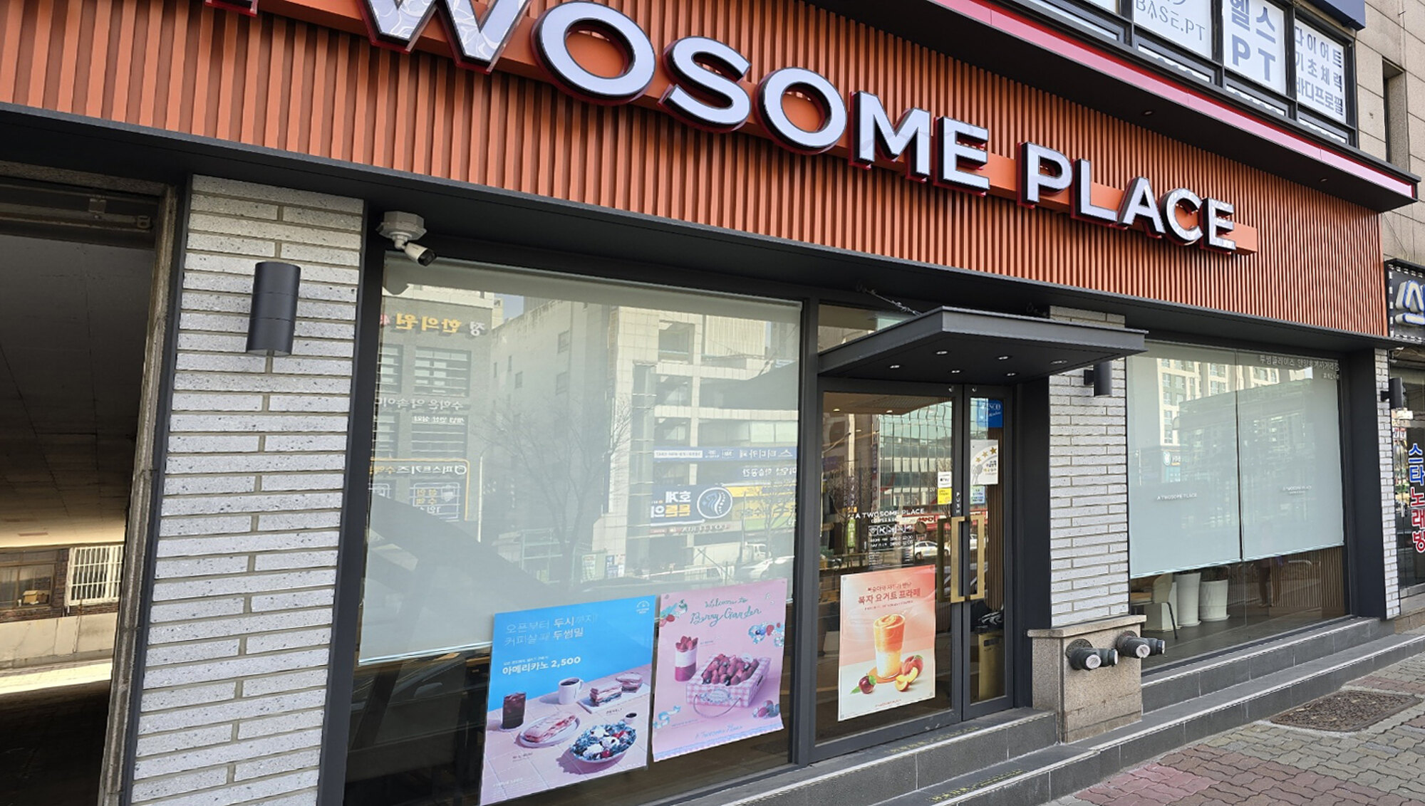 안양역 투썸플레이스 외부를 비스듬히 본 모습, 통창 두 칸에 화이트 롤스크린이 내려진 장면